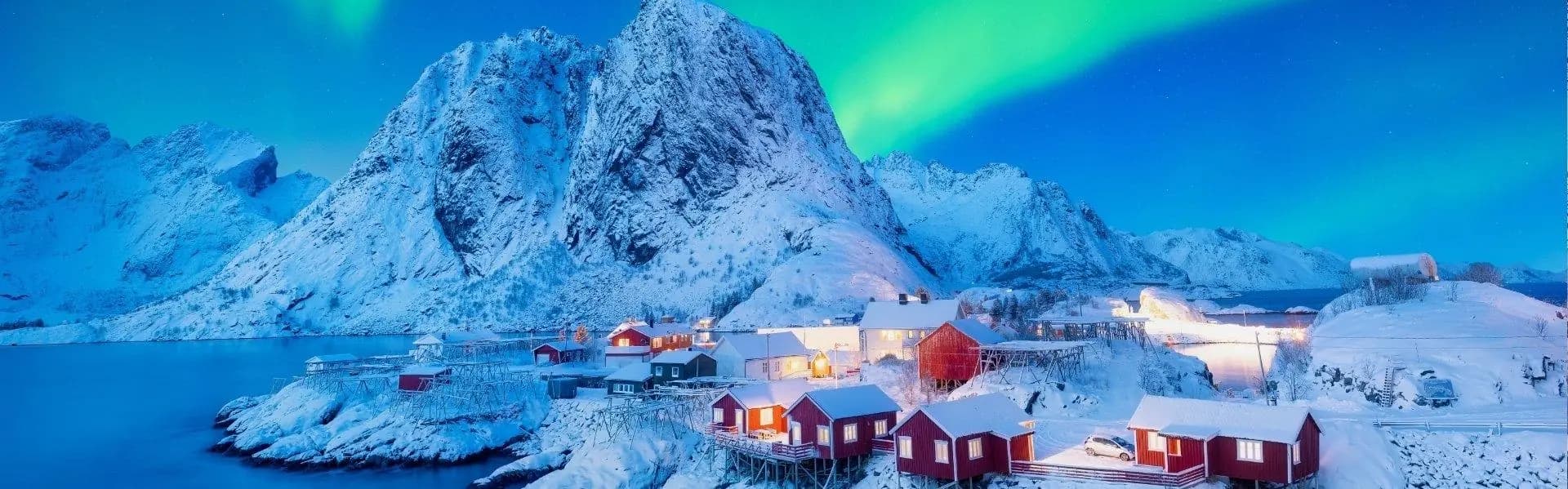 Rode vissershuisjes in de sneeuw onder het noorderlicht op de Lofoten
